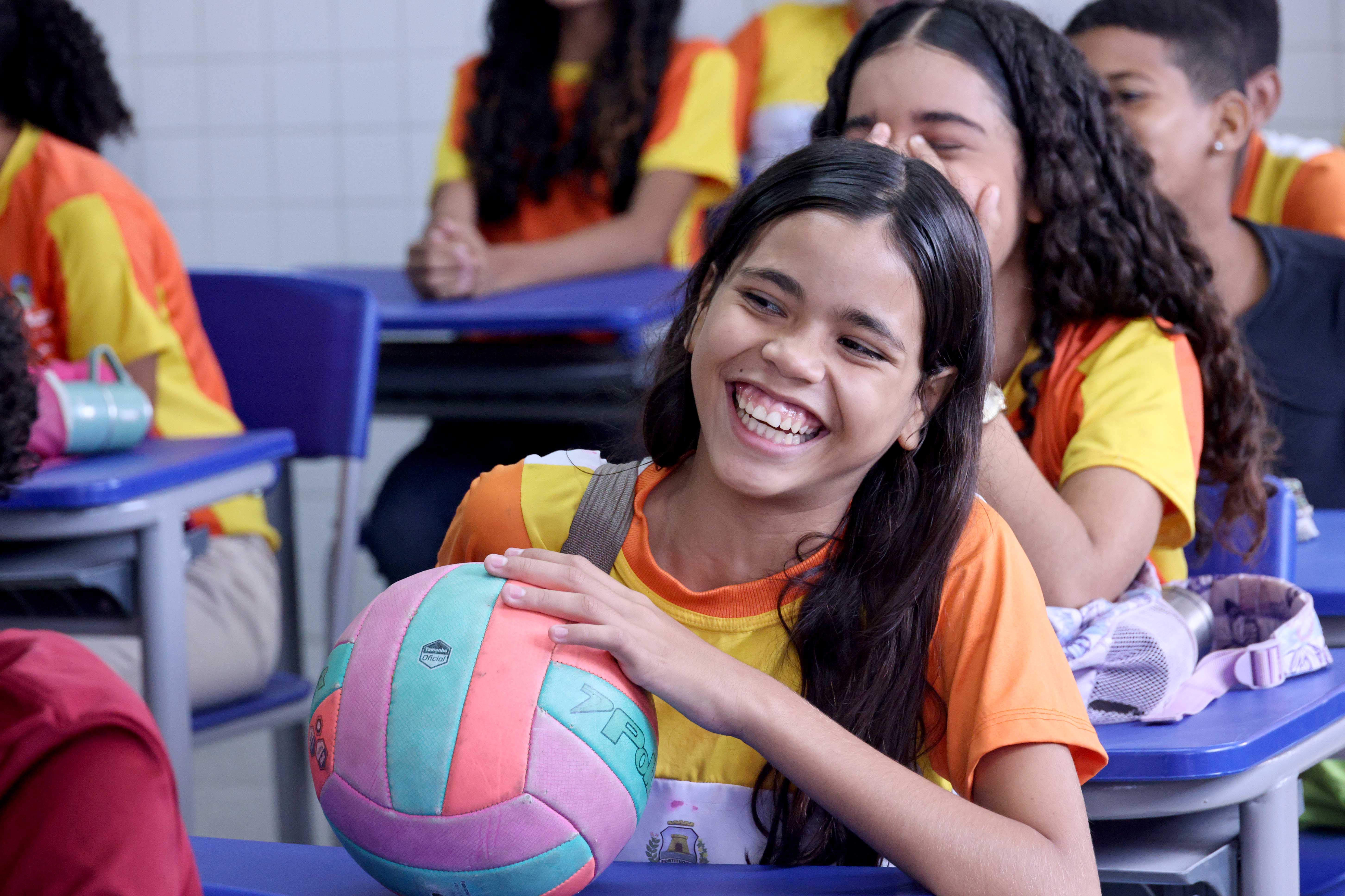 aluna sorrindo segurando bola de volei